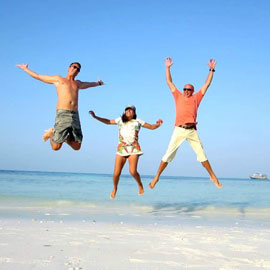 BALI HOLIDAY Three adventurous friends joyously jumping in the air on a tropical white sand beach