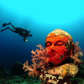 Underwater-Temple Scuba diver observing with an underwater light excitements of an underwater temple in Bali